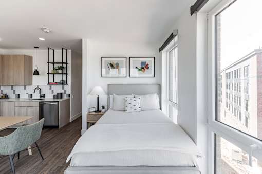A modern bedroom with a large bed and a kitchen area in the background at Anthem House Apartment , Alabama, 35806