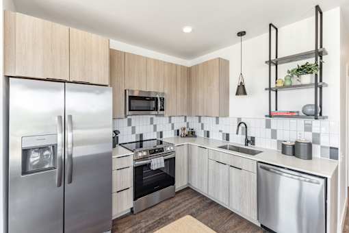 A modern kitchen with stainless steel appliances and wooden cabinets at Anthem House Apartment , Huntsville