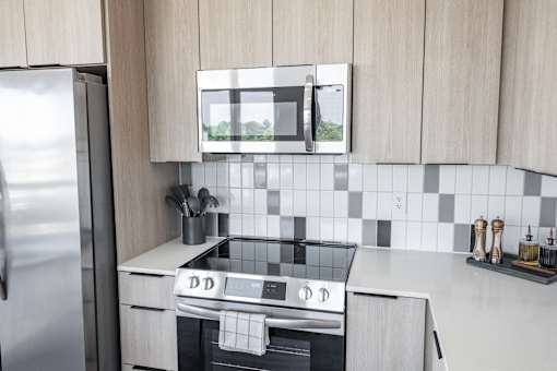 A modern kitchen with a stove top oven and a microwave above it at Anthem House Apartment , Huntsville, 35806