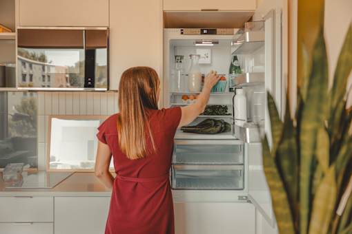 a woman is standing in front of an open refrigerator at Scout Living, powered by Placemakr Apartments, Georgia