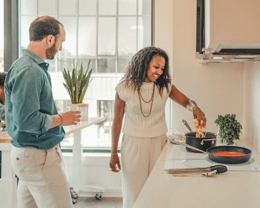a man and woman cooking food in a kitchen at Scout Living, powered by Placemakr Apartments, Atlanta, Georgia