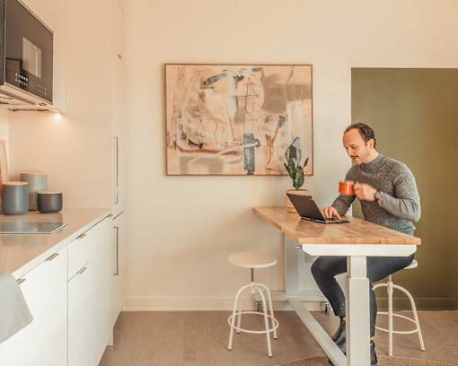 a man sitting at a kitchen table using a laptop computer at Scout Living, powered by Placemakr Apartments, Atlanta