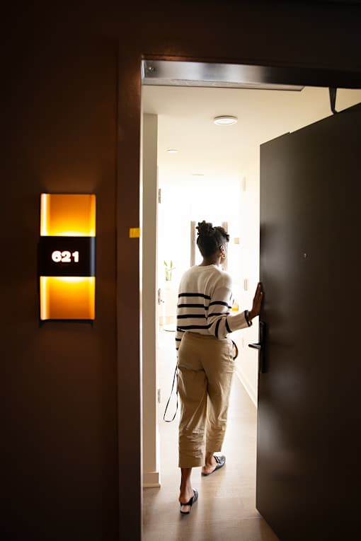 a woman is standing in front of a door with her hand on a door handle at Scout Living, powered by Placemakr Apartments, Atlanta, 30308