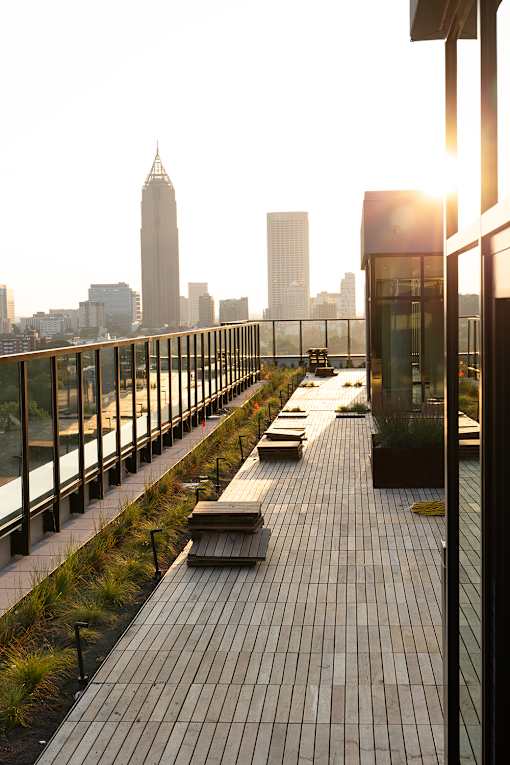 a rooftop deck with benches and a city skyline in the background at Scout Living, powered by Placemakr Apartments, Georgia 30308