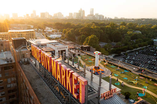 an aerial view of an amusement park with a city in the background at Scout Living, powered by Placemakr Apartments, Georgia 30308