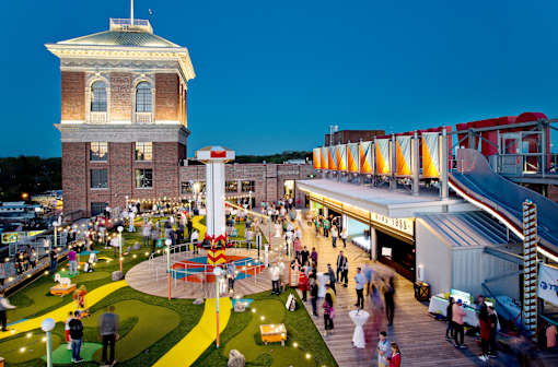a crowd of people walking around an amusement park at night at Scout Living, powered by Placemakr Apartments, Atlanta