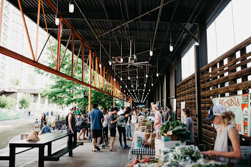 people shopping at a farmers market in a building with wooden beams at Scout Living, powered by Placemakr Apartments, Atlanta, GA, 30308