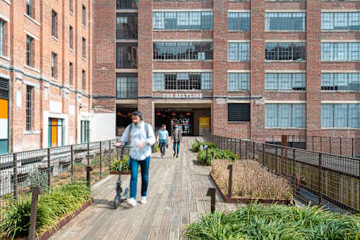 people walking on a boardwalk in front of a building at Scout Living, powered by Placemakr Apartments, Atlanta, Georgia