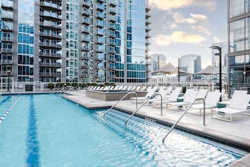 A swimming pool with lounge chairs and a view of a city skyline.
