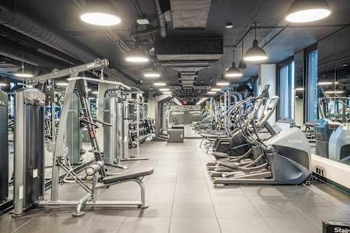 A gym with a variety of equipment including treadmills, stationary bikes, and weight machines at Coda on Half Apartments, Washington, DC 20003