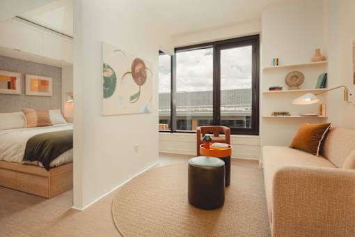 a living room with a large window and a couch and a chair at Scout Living, powered by Placemakr Apartments, Atlanta, GA