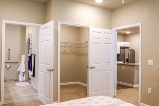 a closet with doors open to a bathroom and a bed