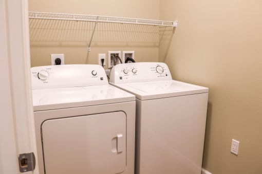 a washer and dryer in a laundry room with a shelf above them