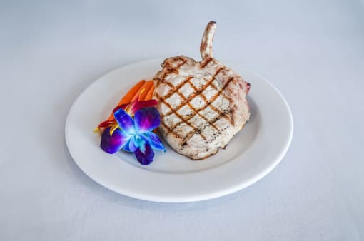 a piece of meat on a white plate with flowers