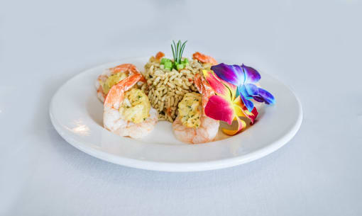 a plate of food with rice and shrimp and a flower