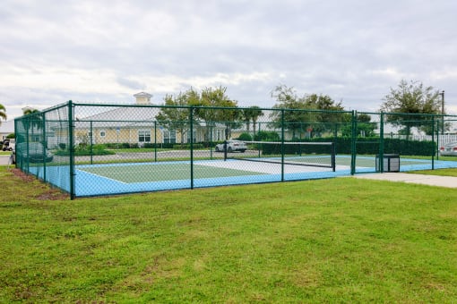 a tennis court with a green fence and a green lawn