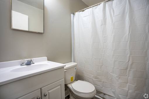A white toilet sits next to a white sink in a small bathroom.
