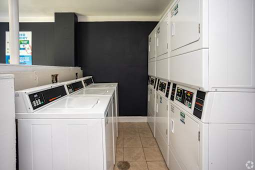 A row of white front loading washing machines in a laundromat.