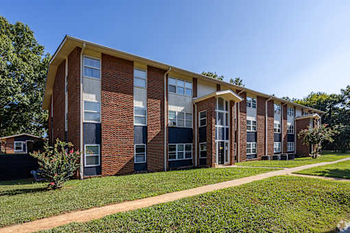 A red brick building with a yellow roof and a green lawn in front.
