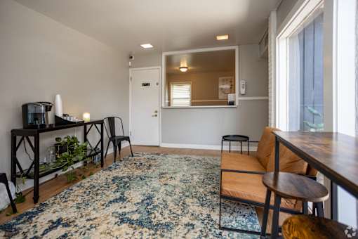 A living room with a rug, a table, and a chair.