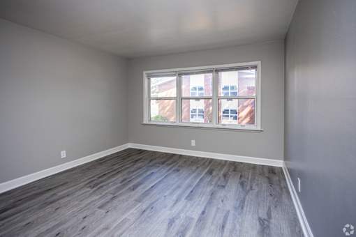 A room with a large window and wooden flooring.