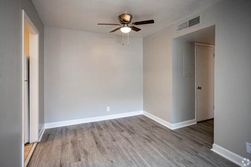 A room with a ceiling fan and wooden flooring.