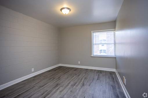 A room with a window and wooden flooring.