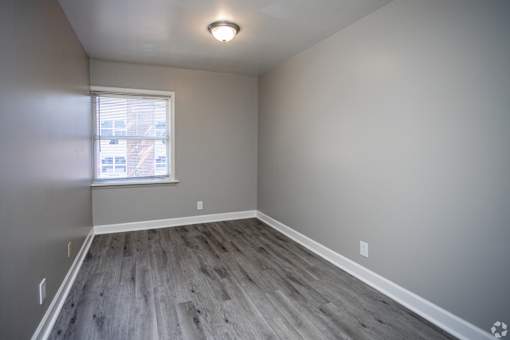 A room with a window and wooden flooring.