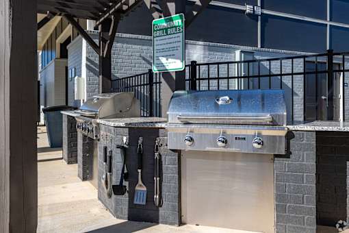 A sign that says "Community Grill Rules" hangs above a grill.
