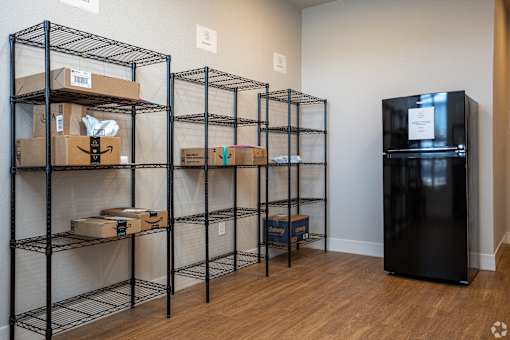 A room with shelving units and a black fridge.