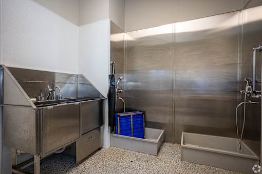 A stainless steel kitchen with a sink and a blue container.