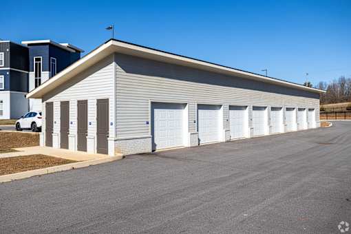 A long building with a grey roof and white garage doors.