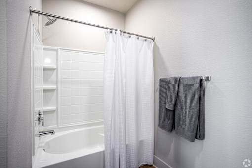 A white bathroom with a white tub and a white shower curtain.