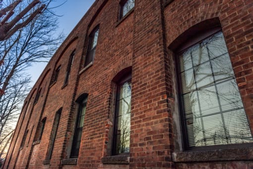 an old brick building with large windows and trees in the background