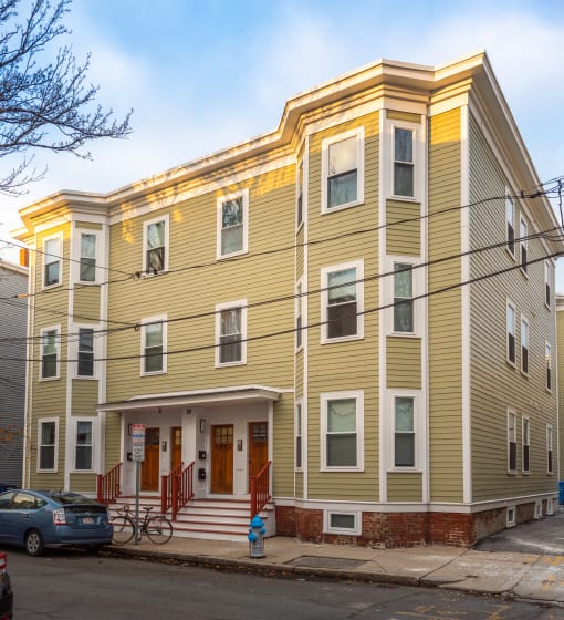 a yellow apartment building with a car parked in front of it