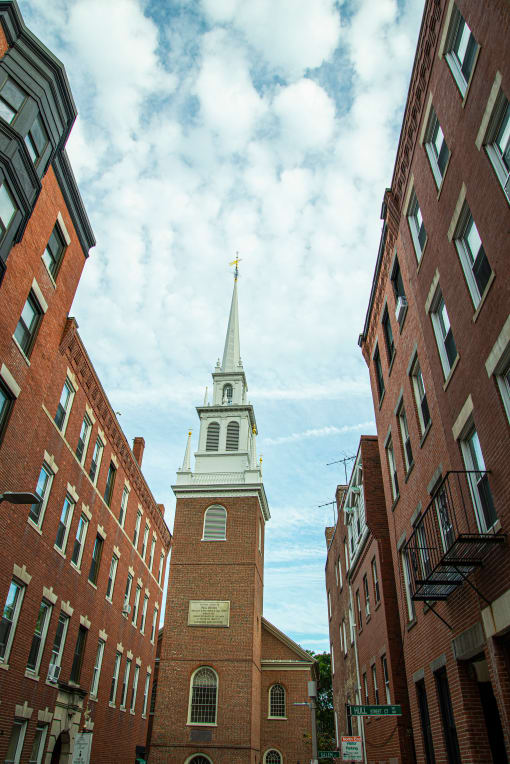 a church tower in the middle of two brick buildings