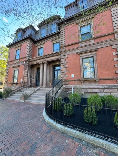 the front of a brick building with stairs and a black fence