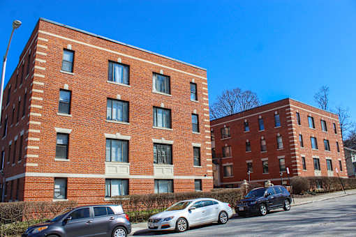 A red brick building with cars parked in front.