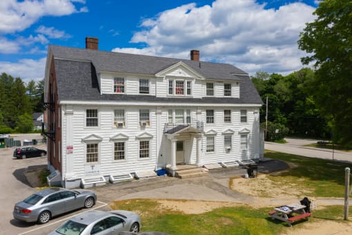 a large white house with a gray roof on a sunny day