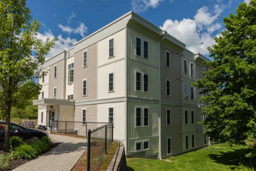 a large apartment building with green grass and trees in front of it