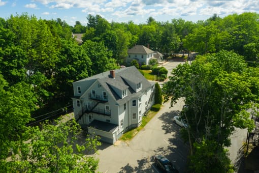an aerial view of a large white house surrounded by trees