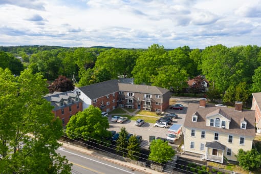 an aerial view of a brick apartment complex with trees in the background