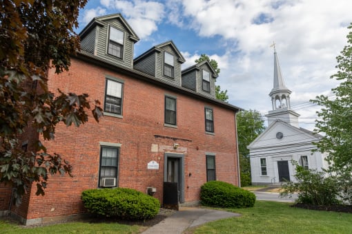 a brick building with a white church steeple in the background