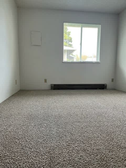 A room with a carpeted floor and a window.