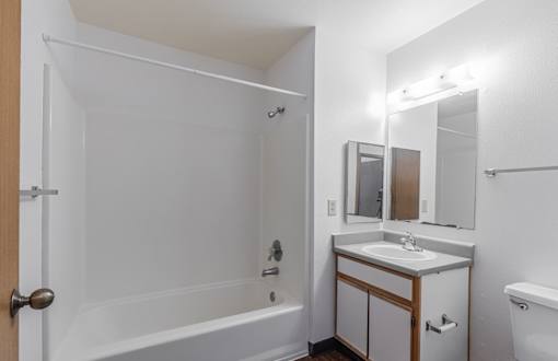 A white bathroom with a sink, mirror, and bathtub.