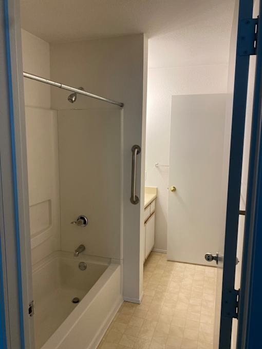 A white bathtub with a shower head and faucet.