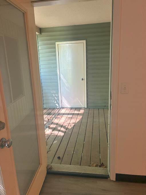 A white door is open to a deck.