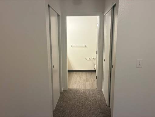 A hallway with a carpeted floor and white walls.