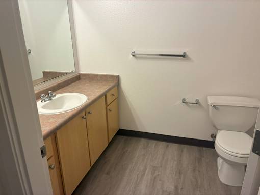 A bathroom with a toilet, sink, and wooden cabinets.