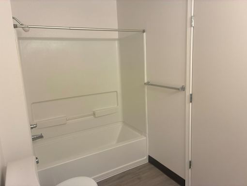 A white bathroom with a toilet and a walk-in shower.
